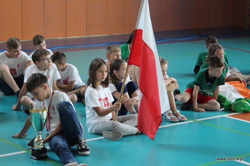 dzieci siedzące na podłodze, dziewczynka trzyma flagę Polski