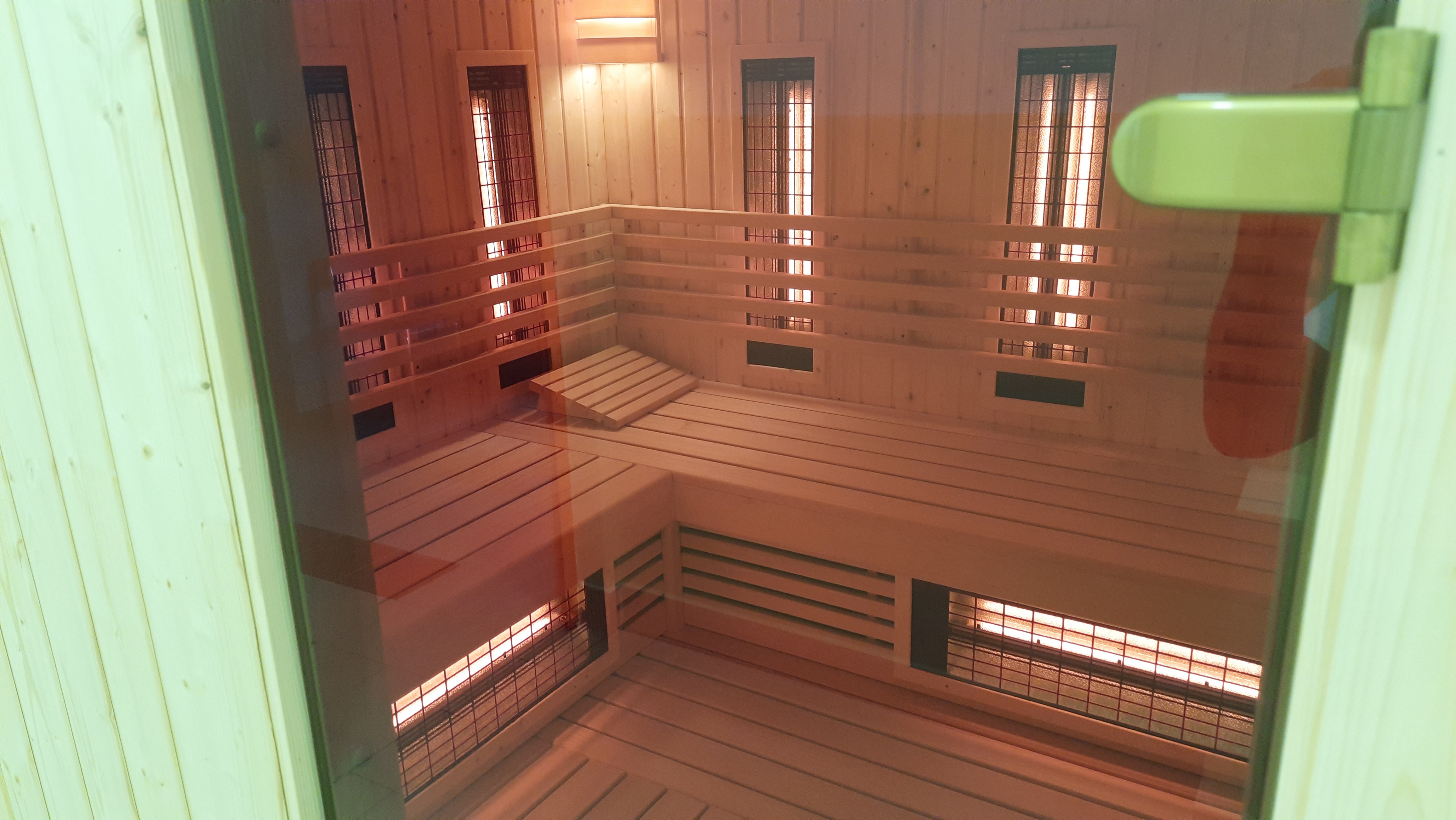 Na zdjęciu widoczne przez szklane drzwi, drewniane wnętrze sauny 
