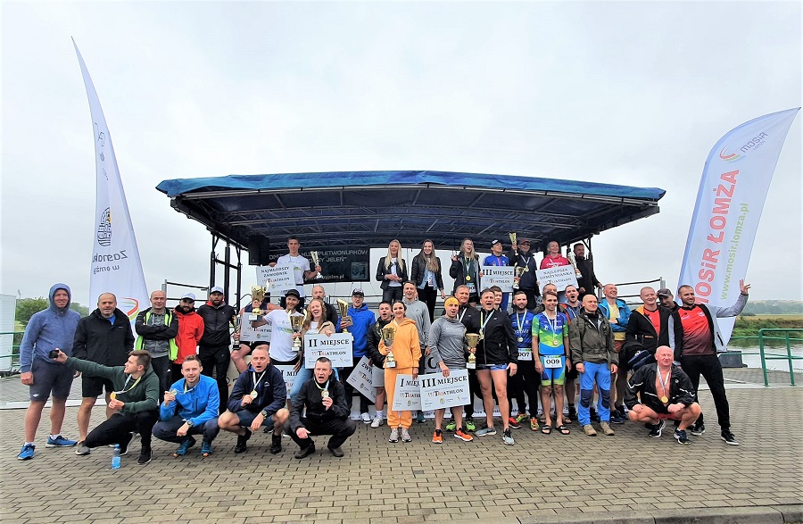 zdjęcie przestawiające grupę zawodników triathlonu stojących na scenie na bulwarach