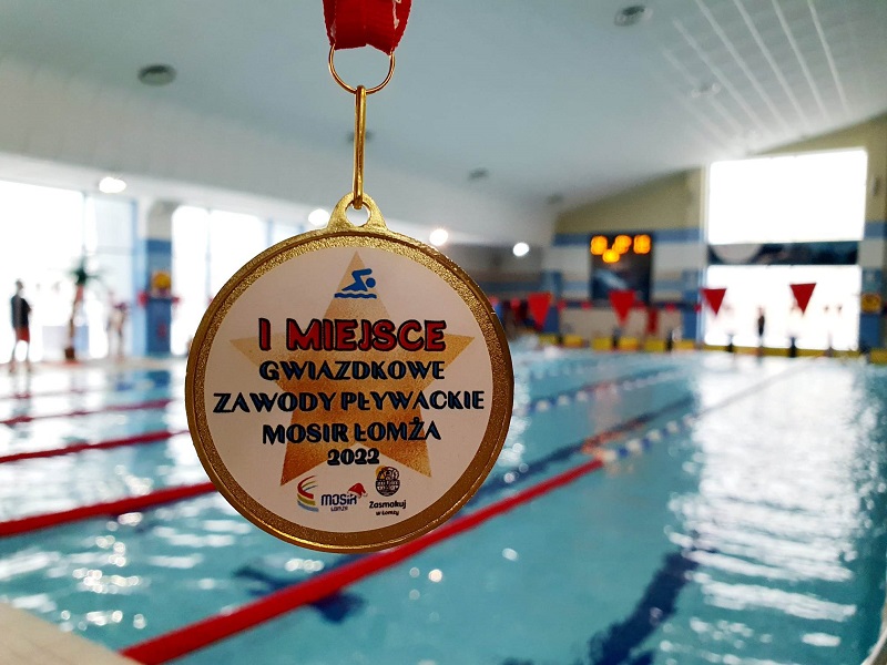 zdjęcie przedstawia medal na tle torów do pływania w Parku Wodnym