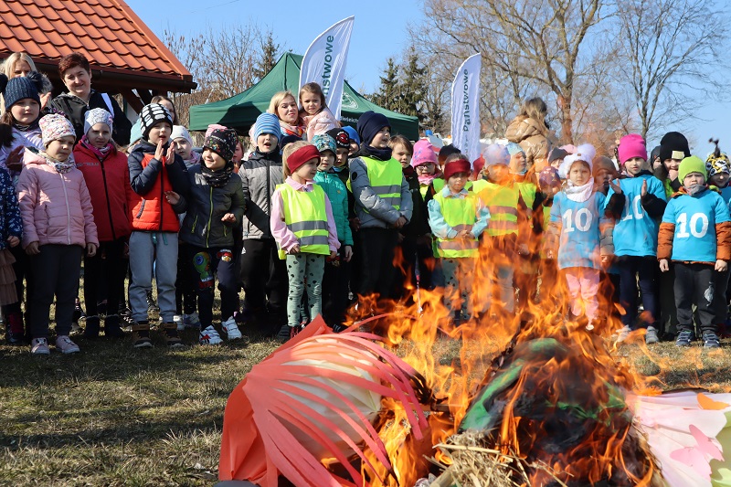 Duże skupisko przedszkolaków zgromadzonych wokoło ogniska, na którym palona jest marzanna.