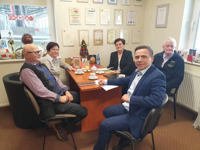 zdjęcie 4 członków stowarzyszenia Aktywny Senior i dyrektora MOSiR siedzących przy biurku
