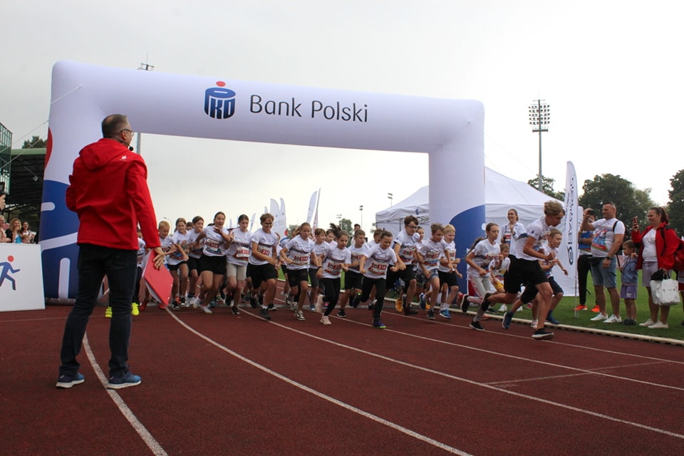 zdejęcie przedstawiające grupe dzieci na bieżi stadionu startującą w biegu