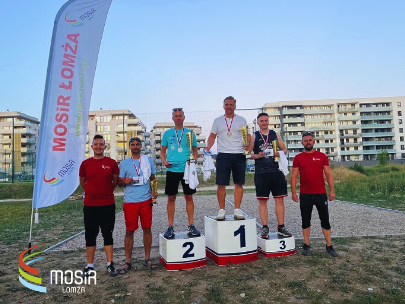 Zawodnicy na podium, trzymają nagrody.