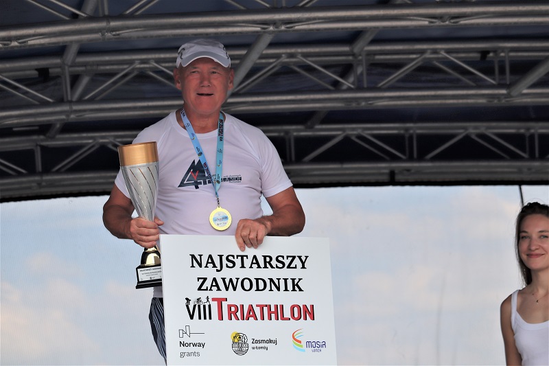 zdjęcie przedstawiające zwycięzców triathlonu na podium na scenie