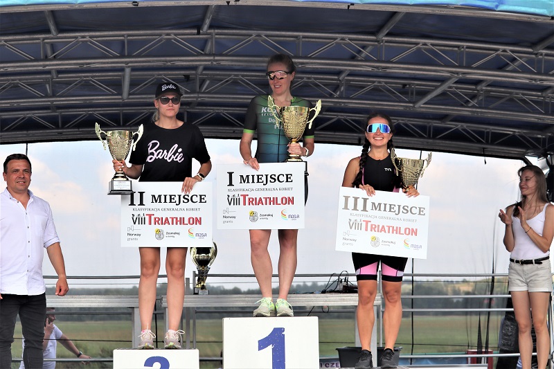 zdjęcie przedstawiające zwycięzców triathlonu na podium na scenie