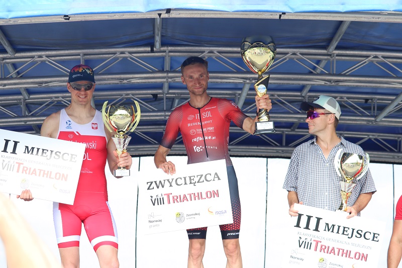 zdjęcie przedstawiające zwycięzców triathlonu na podium na scenie