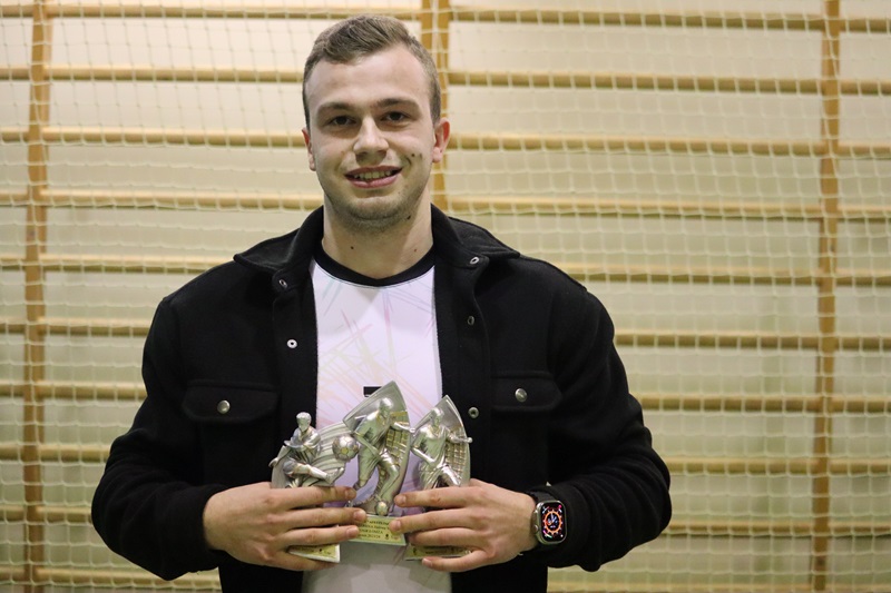 Zdjęcie przedstawia zawodnika, z 3 statuetkami.