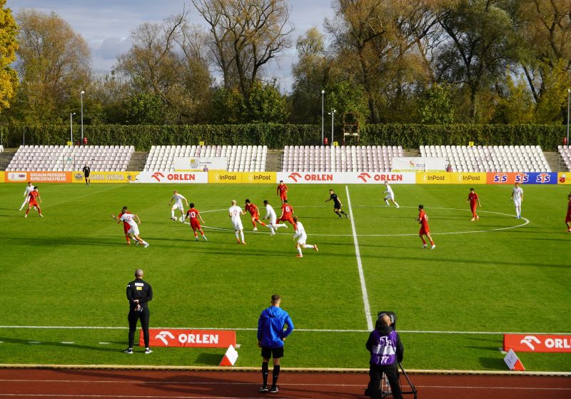zawodnicy grający mecz piłki nożnej na murawie stadionu