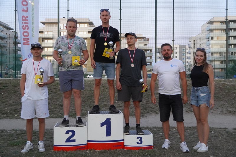 Zdjęcie przedstawia zwycięzców VI Turnieju w Boule. Wszyscy mają puchary i stoją na lub obok podium.