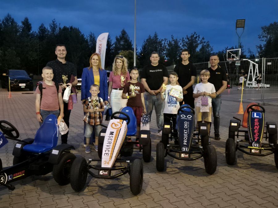 Zwycięzcy I Wyścigu Gokartami MOSIR Łomża wraz z dyrektor Krynicką Bernadetą i partnerami wydarzenia, w tle gokarty