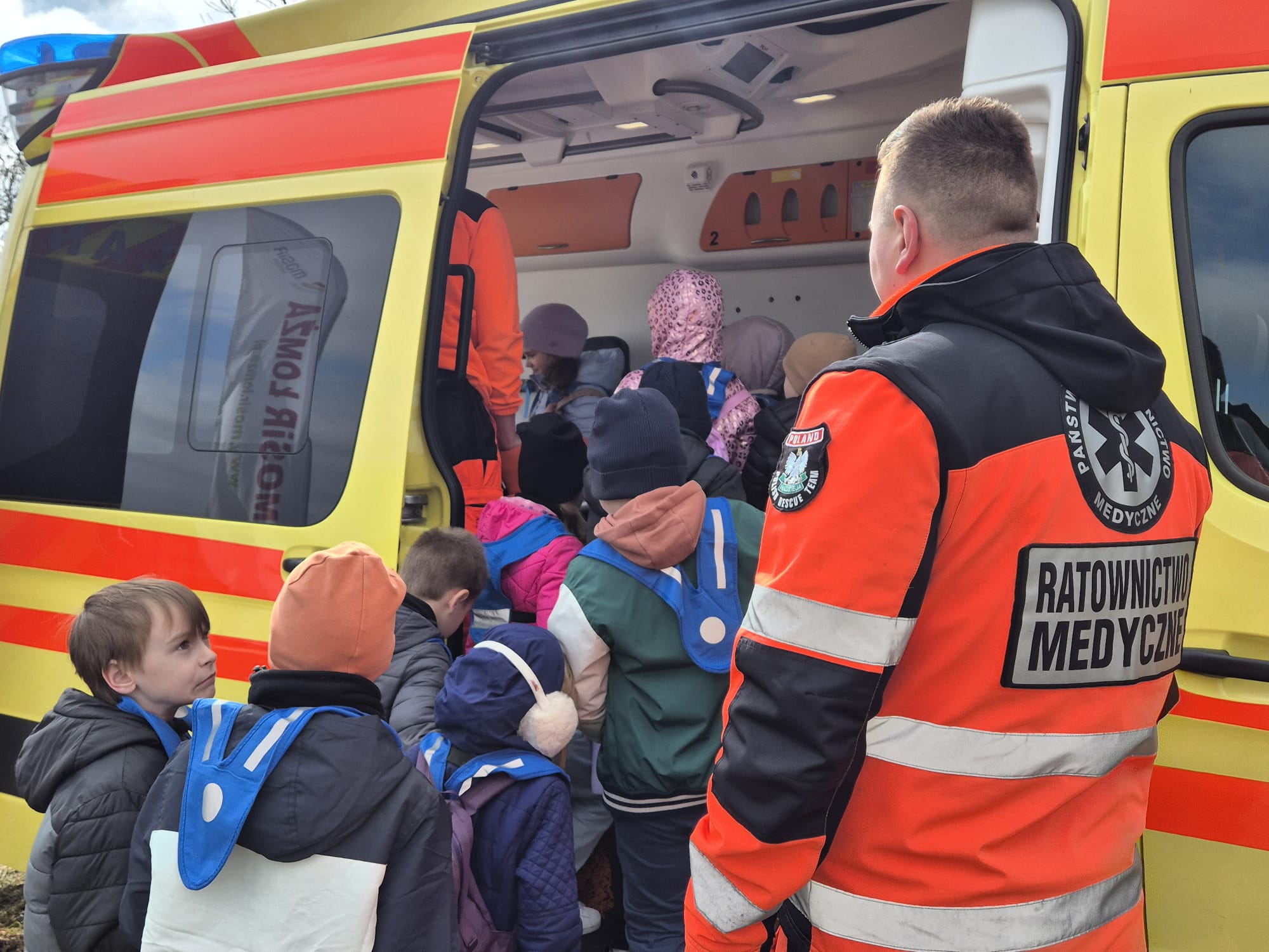 dzieci wchodzące do karetki z ratownikiem medycznym